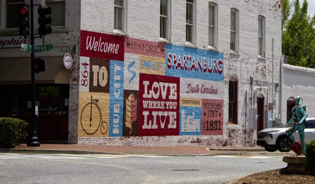 Downtown Spartanburg mural reading 'Welcome to Hub City – Love Where You Live' on a historic brick building near Carolina Cloudz, emphasizing local pride and community roots.