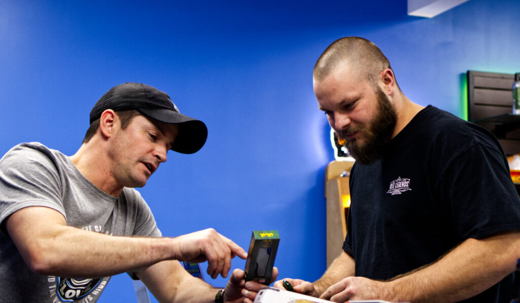 Carolina Cloudz team member Jude and a customer reviewing a hemp product at the checkout counter, offering personalized service and product education in-store.